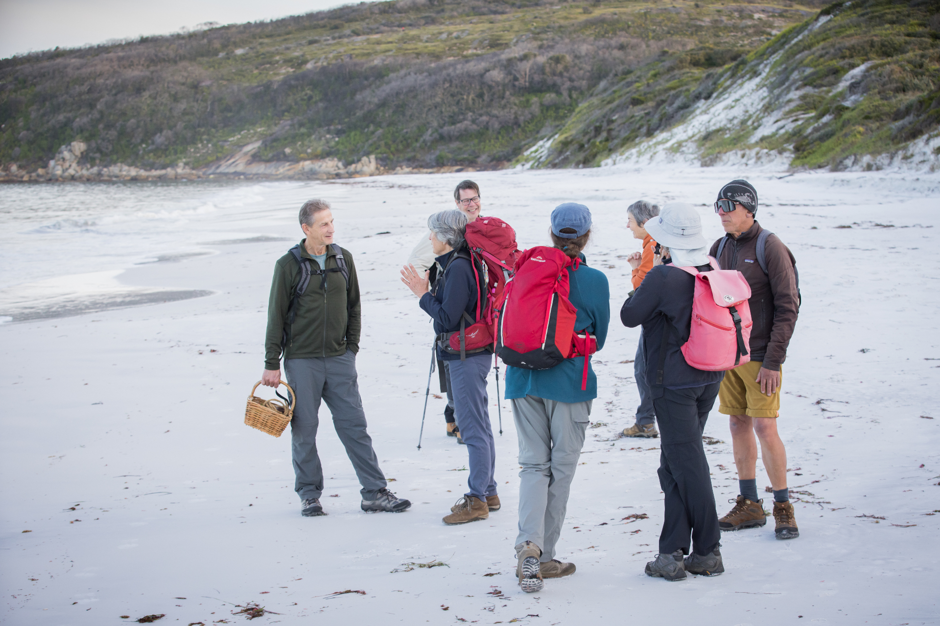 A small group gathered with a picnic basket on a white-sand Albany beach
